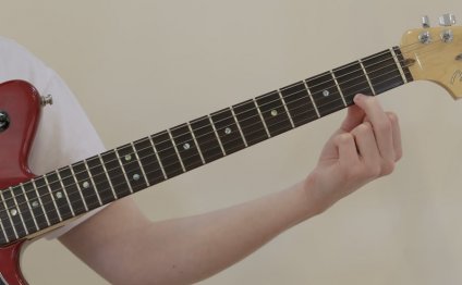 Man placing finger on guitar