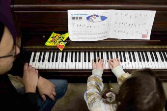 Guitar, drums and piano instructor Loren Kranz (left) listens to Natalya Andrews, 8, play